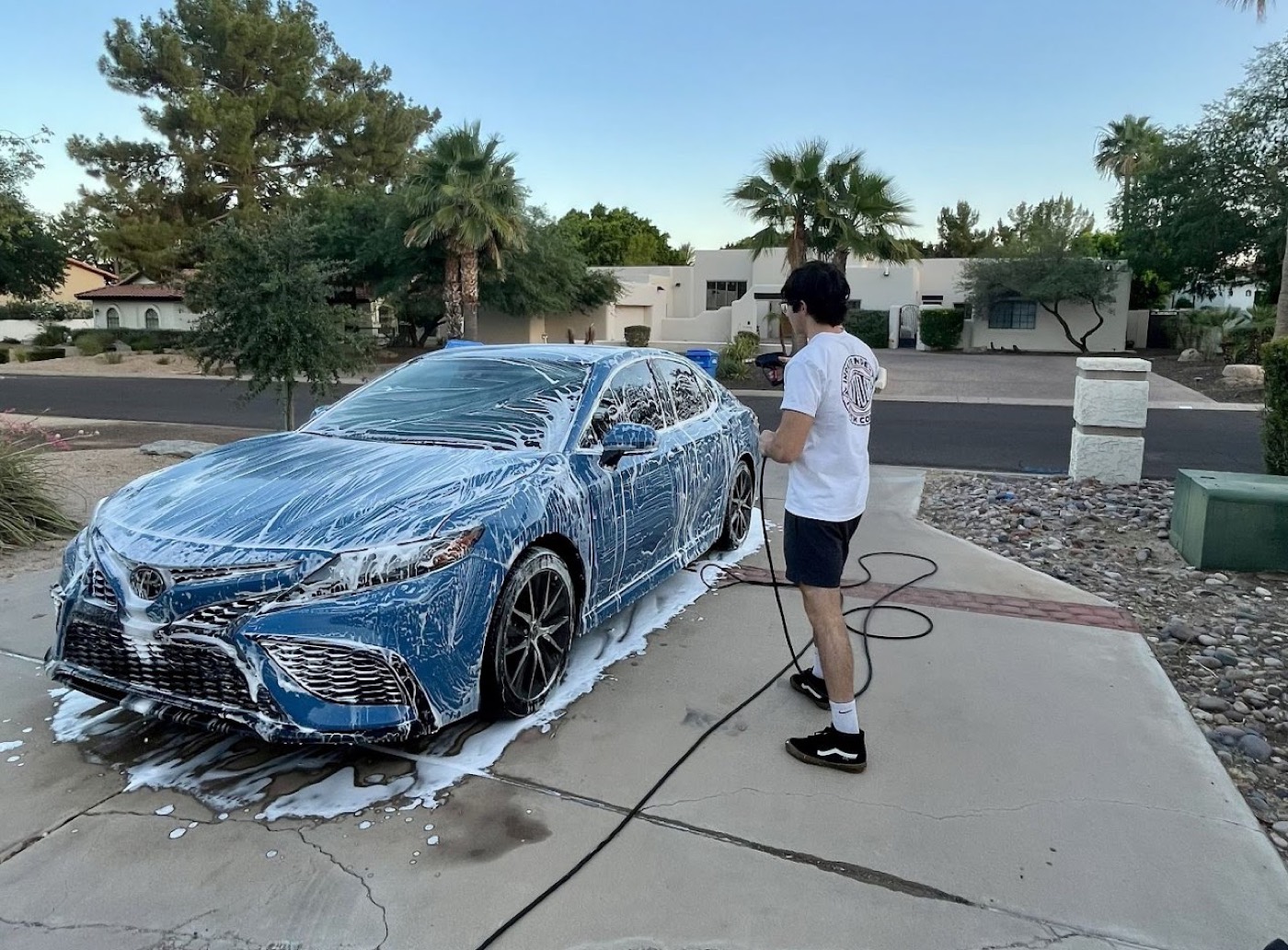 Snowzan detailing a foam-covered sedan in a Phoenix driveway