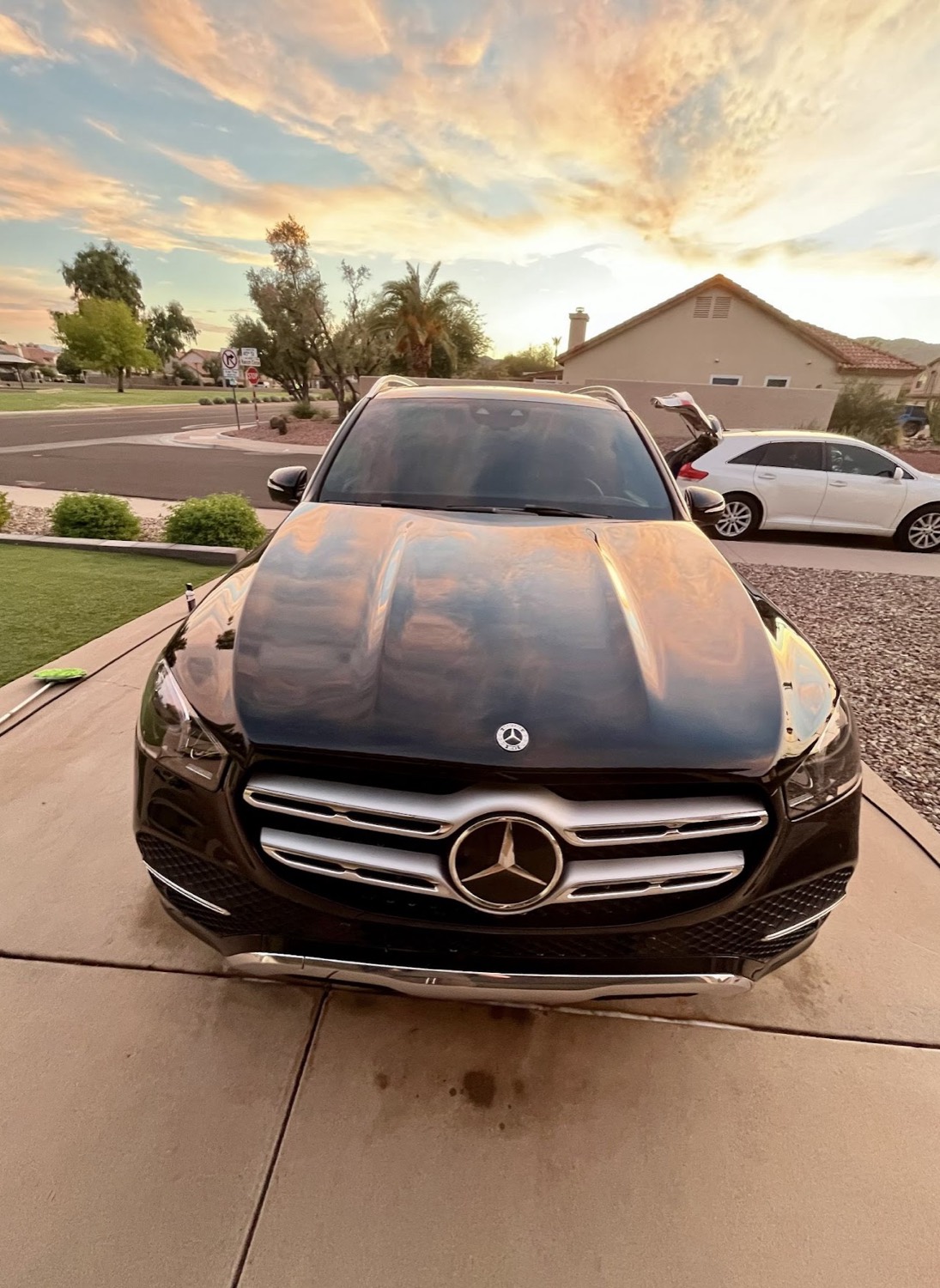 Black Mercedes GLE with a mirror-gloss finish parked in a driveway at sunset