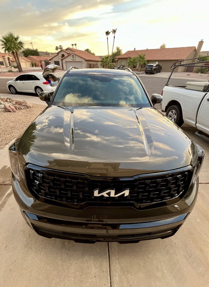 Dark green Kia Sorento with a glossy exterior finish at sunset