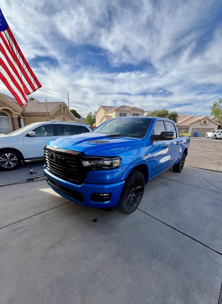 Blue Ram 1500 truck detailed in a driveway under an American flag
